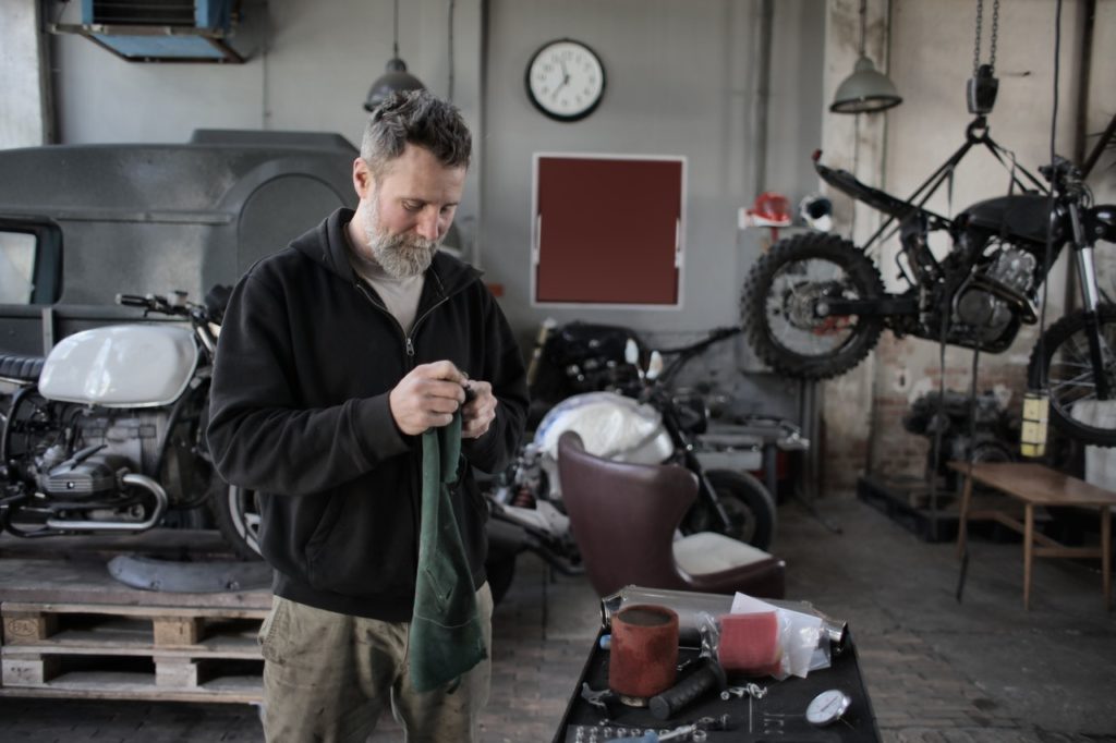 Small business owner in his bike shop fixing a motorcycle.