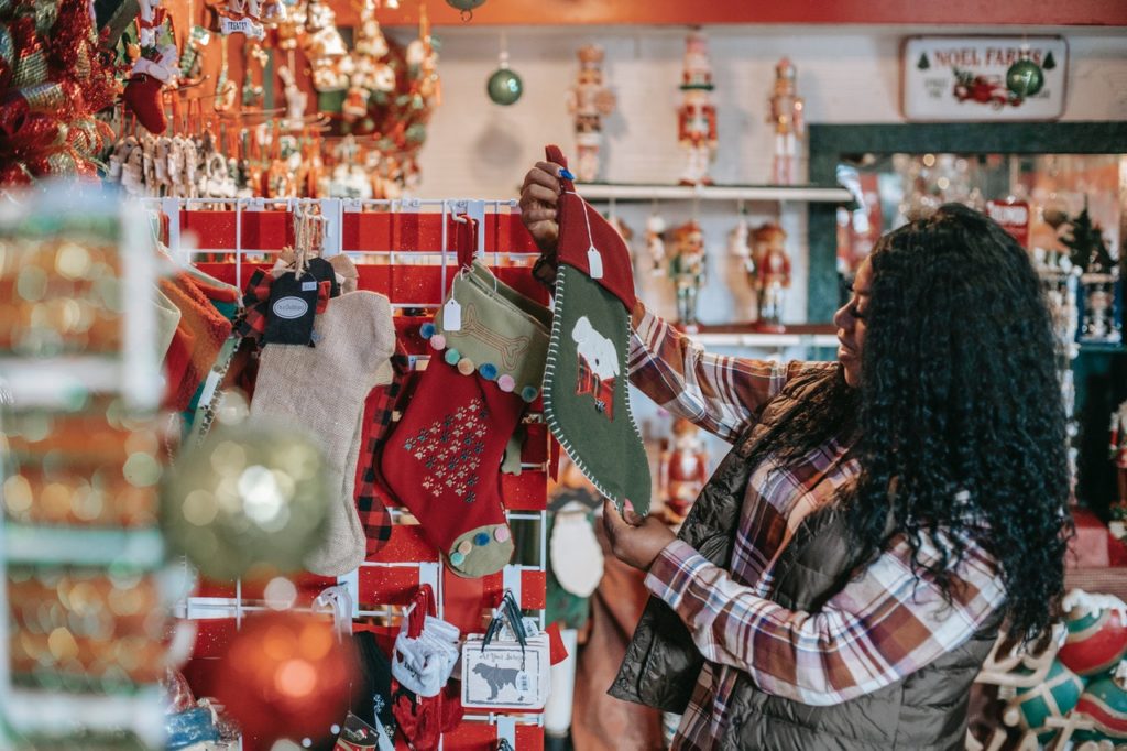 Female part-time employee holding Christmas stocking at store.